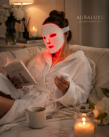 Woman relaxing on a sofa reading a book while wearing the Auraluxe LED mask